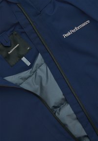 Marineblaue Jacke mit leichtem Design, glattem Innenfutter, Reißverschluss und PeakPerformance-Logo in leichter Stickerei.