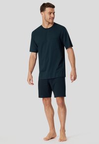 Camiseta de manga corta azul marino con un sutil patrón de puntos y bolsillo, combinada con pantalones cortos a juego. Fabricada con un tejido suave, diseñada para la comodidad.