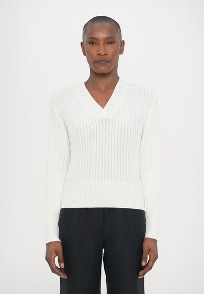 Suéter blanco de canalé con cuello en V y mangas largas, que presenta finas rayas verticales y un dobladillo ceñido. Textura suave, tejido ligero.