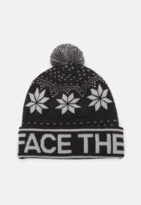 Knit beanie mustassa värissä, jossa on valkoinen lumihiutalekuosi, pom-pom päällä ja "FACE THE" paksulla kirjalla resorissa. Pehmeä tekstuuri.