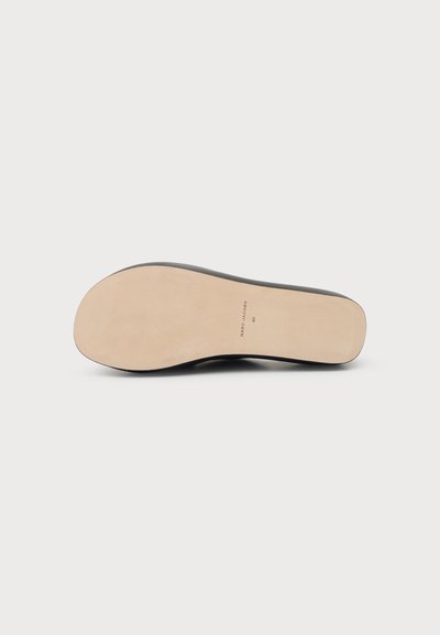 Semelle plate en cuir beige d'une chaussure noire orientée vers le haut sur un fond blanc, avec « Mario Casas 40 » imprimé près de la voûte plantaire.