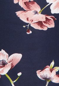 Floral fabric pattern featuring large pink flowers with dark centers on a navy blue background, showcasing detailed petals and green stems.