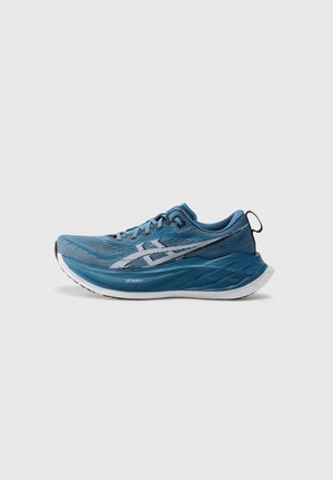 Blaue Sportschuhe mit einem strukturierten Mesh-Obermaterial, kontrastierenden weißen Streifen und einer dicken, gepolsterten Sohle. Verfügt über Schnürsenkel und eine Zuglasche hinten.