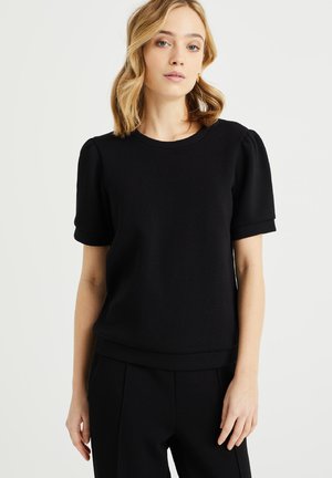Zwarte top met korte mouwen in een ribbelstructuur, ronde halslijn en iets prinselijke mouwen. Zachte stof en een ontspannen pasvorm met een tailleband.