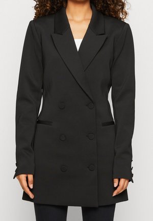 Blazer nero doppiopetto con vestibilità sartoriale, rever a taglio, due tasche frontali e dettagli con bottoni sui polsini. Tessuto dalla texture liscia.