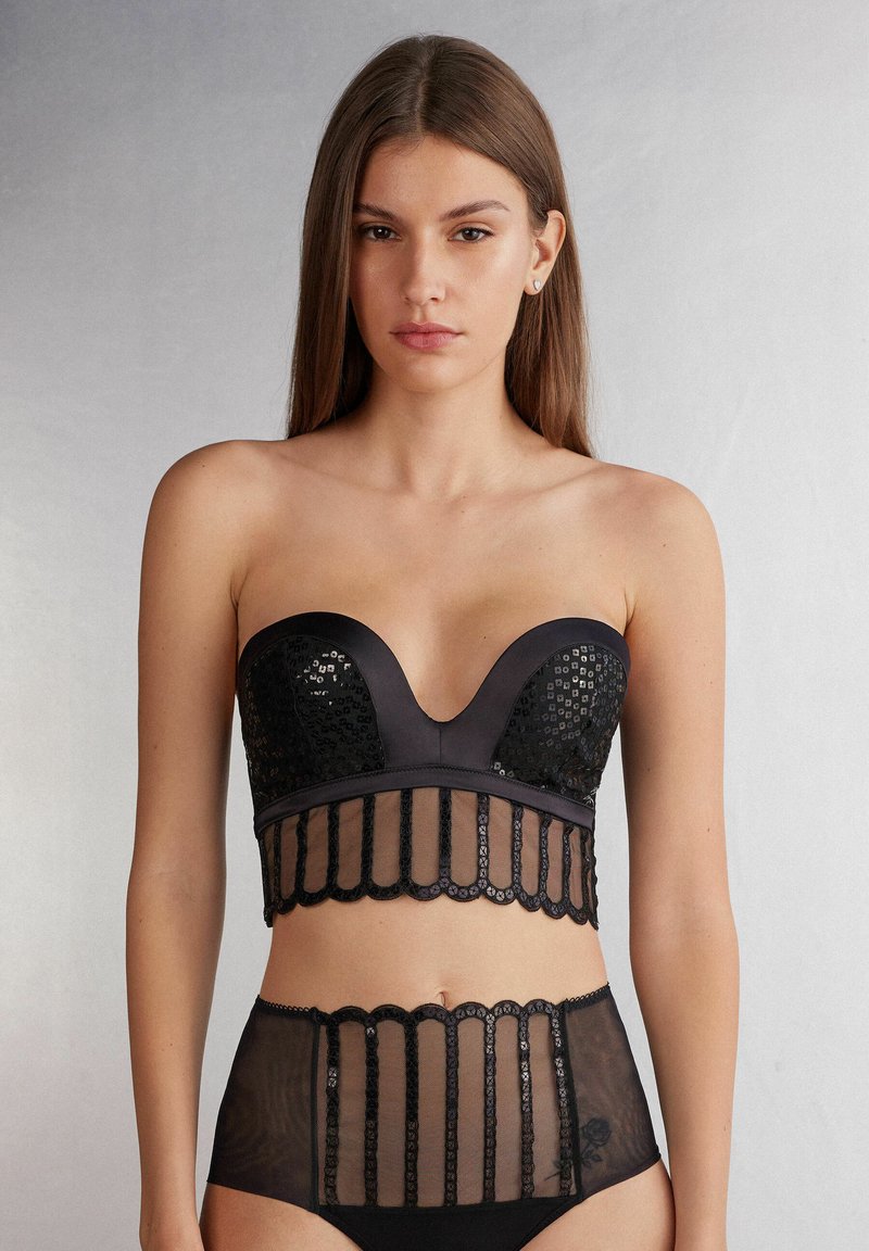 Zwarte bh met een diepe halslijn, versierd met pailletten en kanten details; bijpassende high-waisted slip met doorzichtige panelen en bloemaccenten.