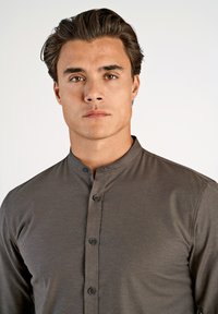 Brązaowa koszula z kołnierzykiem o gładkiej teksturze, z przednią listwą z ciemnymi guzikami i dopasowanym krojem.