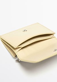Portefeuille en cuir jaune clair plié avec une fermeture à pression argentée, comprenant deux compartiments et une texture intérieure lisse.