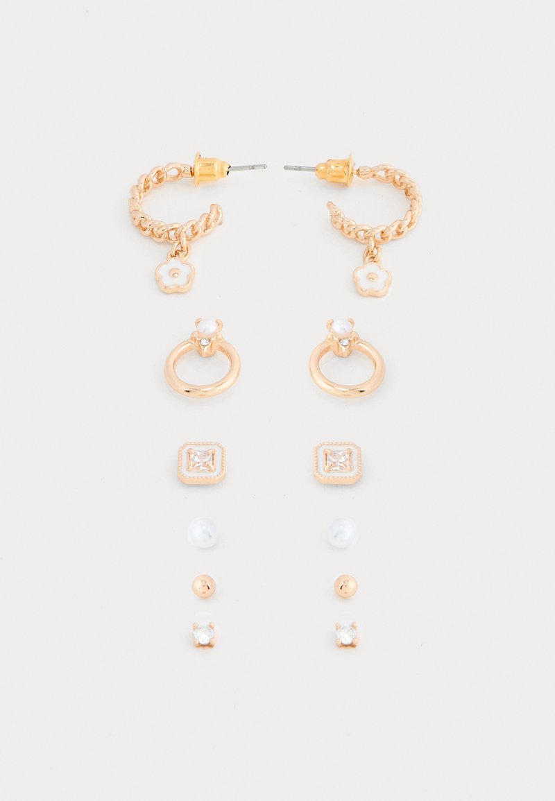 Septynios auksinės spalvos smeigės ir žiedų auskarų poros su gėlių žavesiais, perlais ir skaidriais brangakmeniais, išdėstytos ant balto fono.