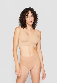 Nude sömlös behå och hög midjeunderkläder i mjukt, stretchigt tyg med en slät yta och v-ringad design. Inga synliga sömmar eller mönster.