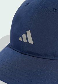 Modrá čiapka z hladkej látky s zakriveným okrajom, vyšívanými očkami a reflexným logom so tromi pruhmi na prednej strane.