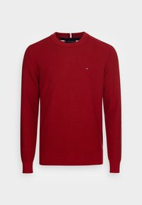 Red knitted sweater with a textured pattern, round neckline, and long sleeves. Features a small logo on the chest and ribbed cuffs.