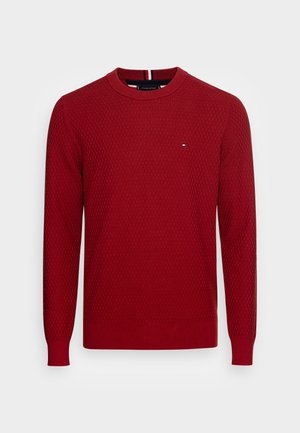 Maglione rosso lavorato a maglia con motivo a rilievo, scollo rotondo e maniche lunghe. Presenta un piccolo logo sul petto e polsini a coste.