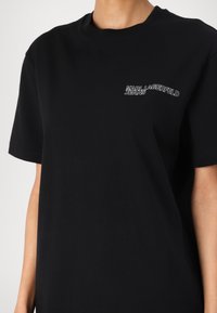 Svart T-shirt i bomull med rund halsringning och korta ärmar. Utmärkande detalj: "KARL LAGERFELD JEANS"-logotyp i silverbroderi.