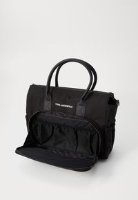 Zwarte nylon schoudertas met dubbele handvatten, ritssluiting en meerdere interne compartimenten met gaas- en gevoerde secties voor organisatie.