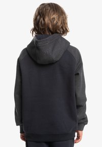 Sudadera con capucha de cuerpo azul marino oscuro y mangas de raglán gris oscuro. Fabricada con un tejido suave y de acabado texturizado, con corte relajado.