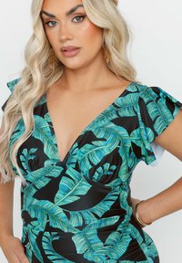Czarna sukienka z żywym, tropikalnym nadrukiem liści w kolorze zielonym, głębokim dekoltem w kształcie V, falbanastymi rękawami oraz marszczeniem w pasie.