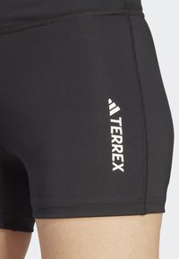 Sorte idrettsshorts med en tettsittende design. Har hvit "TERREX"-merkevare og flatlock-sømmer, laget av et glatt og elastisk materiale.
