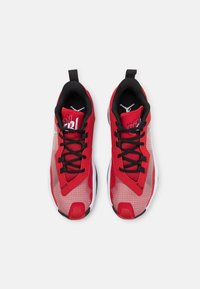 Czerwone buty sportowe z czarnymi siateczkowymi akcentami, teksturowanymi syntetycznymi nakładkami i czarnymi sznurowadłami. Posiadają białą i czarną podeszwę z logo.