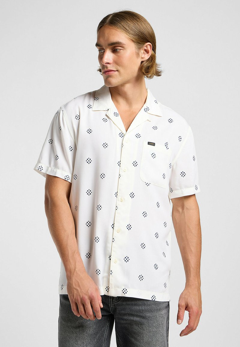 Kortärmad vit skjorta med knappar och ficka, med marinblå diamantmönster och slim fit. Lätt tyg med en slät textur.
