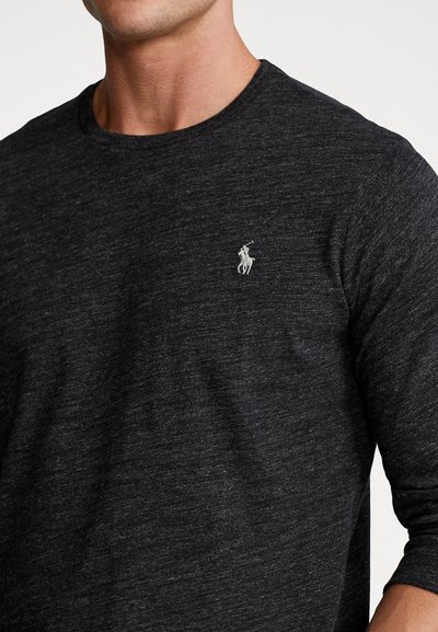 Kolen grijze langemouwen shirt van een gestructureerde stof, met een klein wit geborduurd logo op de linkerborst. Ronde halslijn.