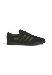 Μαύρο αθλητικό παπούτσι Adidas Stadt με τρεις μαύρες ρίγες, δετό μπροστά και χρυσό λογότυπο στο πλάι, εμφανιζόμενο από την εξωτερική πλευρά.
