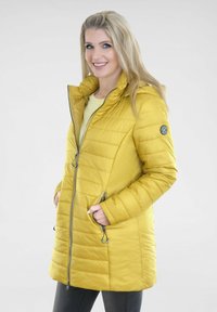 Gelbe Pufferjacke mit Reißverschluss vorne, Kapuze und Seitentaschen. Mit gestepptem Muster und silbernen Hardware-Akzenten. Leichtes Material.