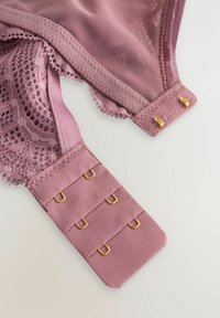 Den rosa behåbandet har nät- och spetsstrukturer, med en slät tygundersida. Guldtonad hårdvara för justering av banden och en förfinad scalloped kant.