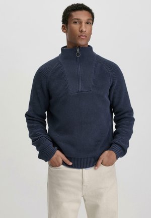 Dunkelblau gestrickter Pullover mit hohem Kragen, Reißverschluss, gerippten Bündchen und Saum. Strukturiertes Muster am Körper, das Stil und Funktion vereint.