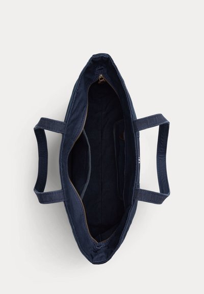 Sac cabas bleu marine avec deux anses et une fermeture éclair ouverte sur le dessus, montrant un intérieur vide avec une doublure en tissu et une petite poche intérieure.