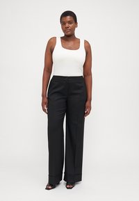 White scoop neck tank top and black wide-leg trousers with a button closure and hem cuffs. Smooth fabric texture with a tailored fit.