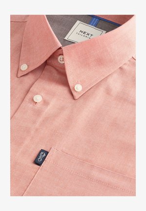 Hellrosa Hemd zum Knöpfen aus strukturiertem Stoff, mit spitzem Kragen, weißen Knöpfen und einem kleinen schwarzen Logotag auf der Tasche.