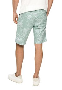 Pantaloni corti verde menta chiaro con un motivo di foglie tropicali bianche, realizzati in un tessuto dalla superficie liscia e con una vita elasticizzata.