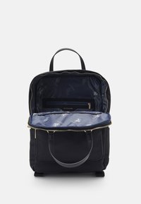 Svart ryggsäck med ett dragkedjeöppning, med ett marinblått inre med ett rutat mönster, läderdetaljer och två bärhandtag.