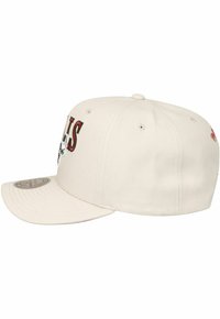 Cremefarbene Kappe mit einem gebogenen Schirm, die gestickten Text und ein Logo in kontrastierendem Schwarz und Rot aufweist. Hergestellt aus strapazierfähigem Stoff.