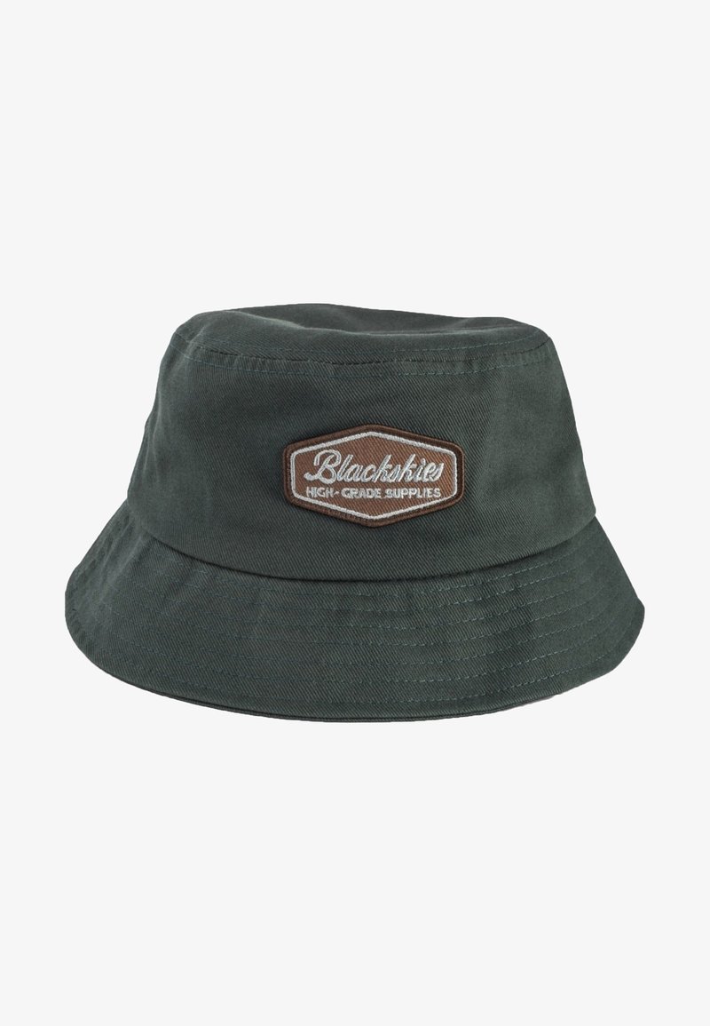 Donkergroene bucket hat van katoen, met een bruine patch met witte geborduurde tekst en textielstructuur. Brede, schuin naar beneden hellende rand.