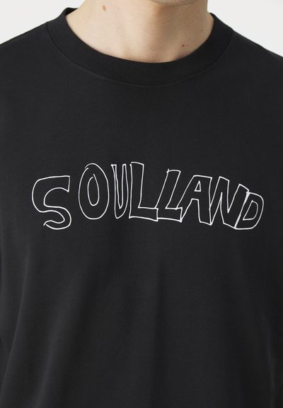 Sort bomulds T-shirt med store, hvide, stiliserede bogstaver "SOULLAND" på brystet. Rund hals, glat tekstur, minimalistisk stil.