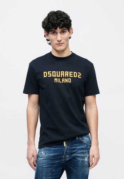 Marineblå bomulds-T-shirt med rund hals, med en fed gul "DSQUARED2 MILANO"-logo på forsiden. Bruges med slidte blå jeans.