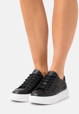 Sorte sneakers i læder med udskåret design, hvid gummisål og sorte snørebånd. Med præget logo på tungen og teksturerede detaljer.