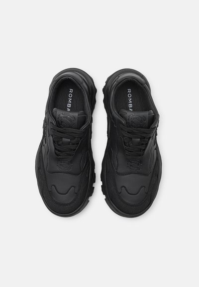 Schwarze Sportschuhe aus einer Mischung aus glattem und strukturiertem Leder, mit runder Form, Schnürdesign und einem auffälligen Logo auf der Innensohle.