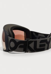Sorte og grå ski-briller med en bred stropp med "Oakley"-logoen, tonede linser og en myk polstret ramme for komfort.