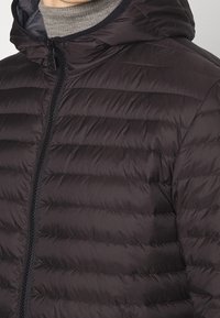 Černá pro šívaná péřová bunda s horizontálním vzorem, polozipem a nastavitelnou kapucí. Vyrobena z hladkého, lehkého materiálu.