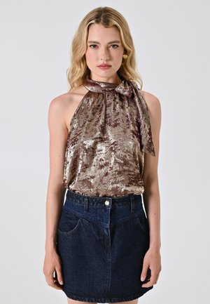 Top a halter in bronzo lucido con dettaglio fiocco, abbinato a una mini gonna in denim scuro con tasche frontali e chiusura con bottone.