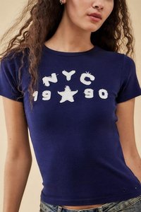 Námornícka modrá priliehavá tričko vyrobené z bavlny, s bielym potlačeným textom "NYC 1990" a dizajnom hviezdy. Krátke rukávy a okrúhly výstrih.