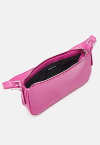 Różowa torebka ze skóry z tłoczeniem imitującym krokodyla, z zamkiem błyskawicznym, szerokim, płaskim paskiem i czarnym wnętrzem.