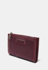 Bordová peňaženka s textúrovaným predným dielom zdobeným cvokmi, so zipsovým zatváraním a nenápadným logom. Hladká koža s lesklým povrchom.