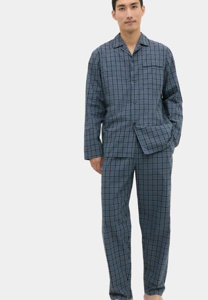 Uomo con pigiama a quadri blu e grigi, camicia con bottoni a maniche lunghe e pantaloni abbinati, in piedi con una mano in tasca.