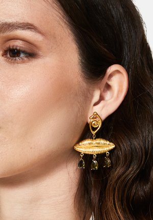 Goldfarbene Ohrringe mit einem gedrehten Drahtdesign in Lippenform, mit zwei dunklen grünen tropfenförmigen Akzenten, die darunter hängen.
