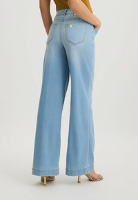 Jeans jeans a gamba larga di colore azzurro chiaro, realizzati in denim, con vita alta, tasche posteriori e un taglio dritto con una texture liscia.