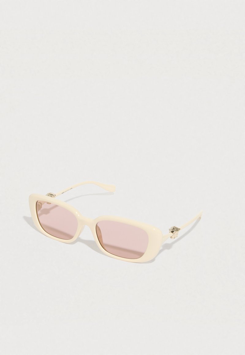 Kremsfarvede rektangulære solbriller med lyserøde glas og dekorative sølvdetaljer på stængerne, vist på en hvid baggrund.